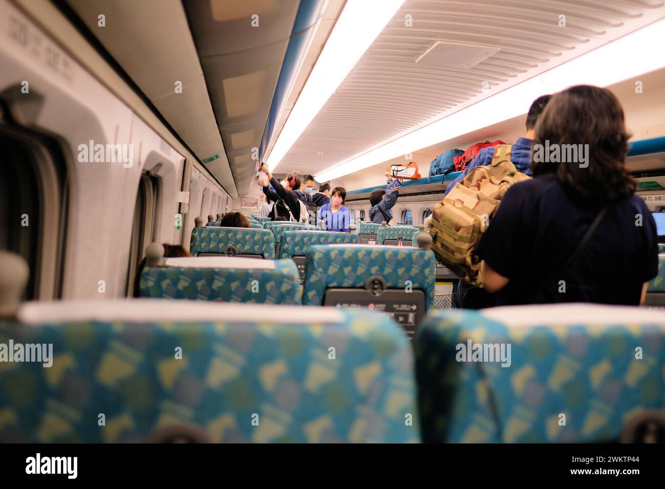 Passengers on board a THSR 700T high speed train car as they walk through the aisle looking for their seat; Taiwan High Speed Rail Corporation; Taipei Stock Photo