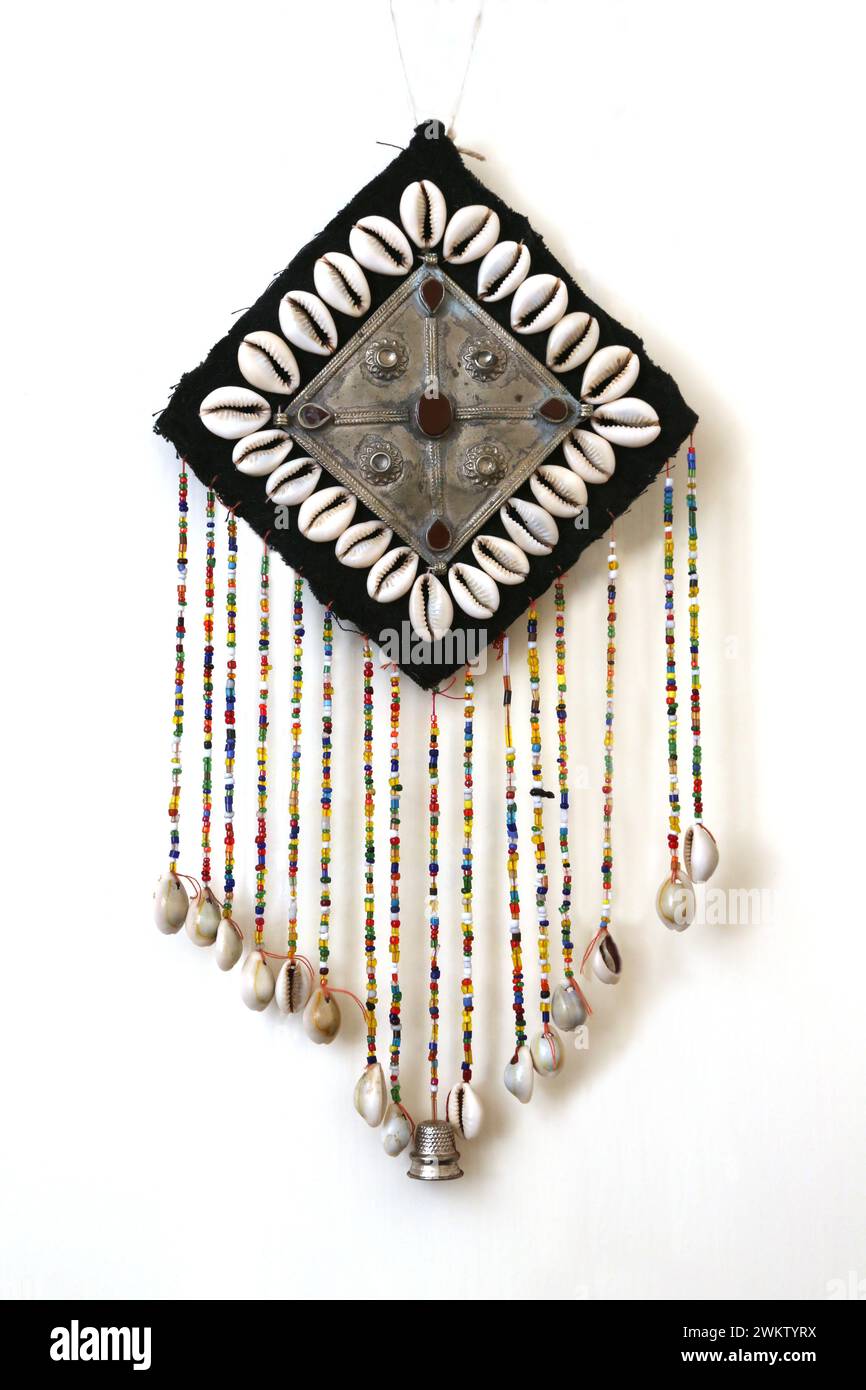 Wall Hanging with a Cross on Metal plate  with Carnelian Stones and Hanging Beads with Cowrie Shells at the End Stock Photo