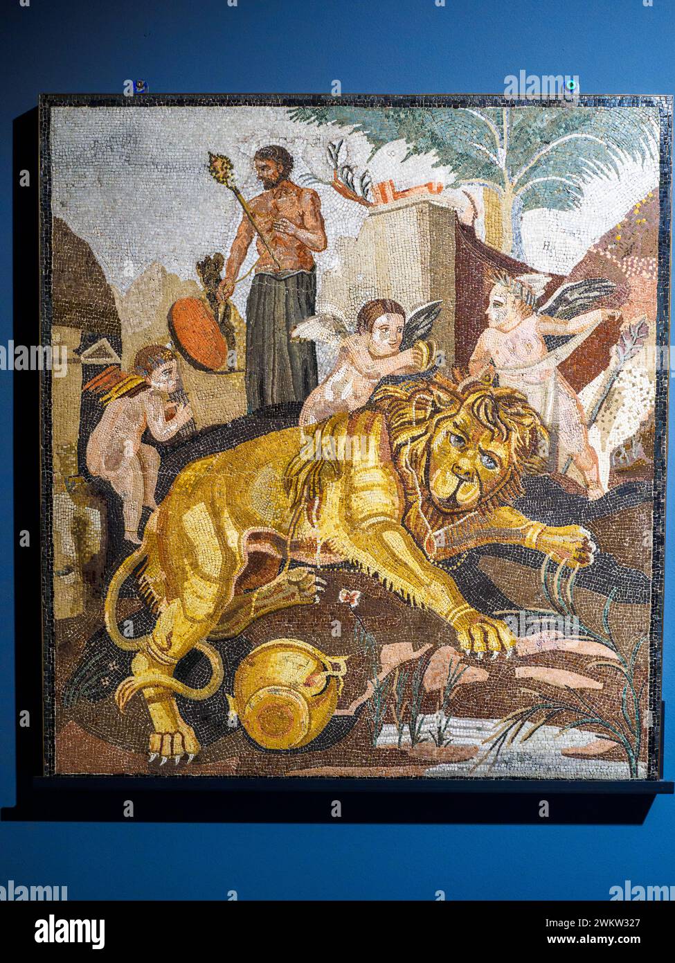 Polychrome Emblema with Lion and Cupids (found in Anzio, rome, Selva Pamphili) - 1st century BC. Extremely minute marble and vitreous paste tesserae- This highly refibed floor emblema represents a scene of Dionysian character, set outdoors. In the foreground, a lion is depicted lying on a rock near a body of water, surrounded by some cupids: two of them, after having stunned it with the wine contained in a large kantharos, are intent on coaxing him with the sound of musical instruments, while a third is about to tie it up with a light cloth - Museo Centrale Montemartini, Rome, Italy Stock Photo
