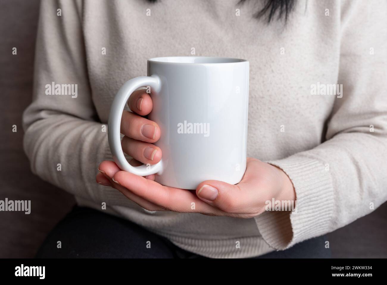 Woman's hands hold a pristine white mug, providing a perfect canvas for promoting mug designs Stock Photo