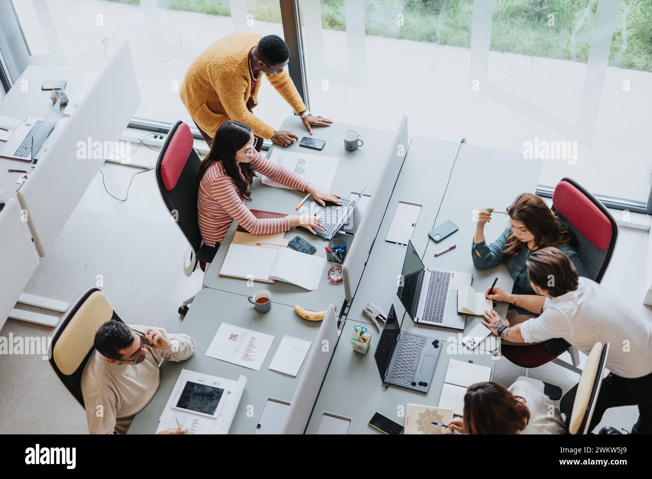 Multicultural group of coworkers collaborating in modern office. Stock Photo
