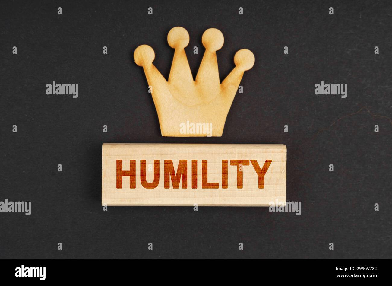 Leader concept. On a black surface there is a wooden crown and a block with the inscription - Humility Stock Photo