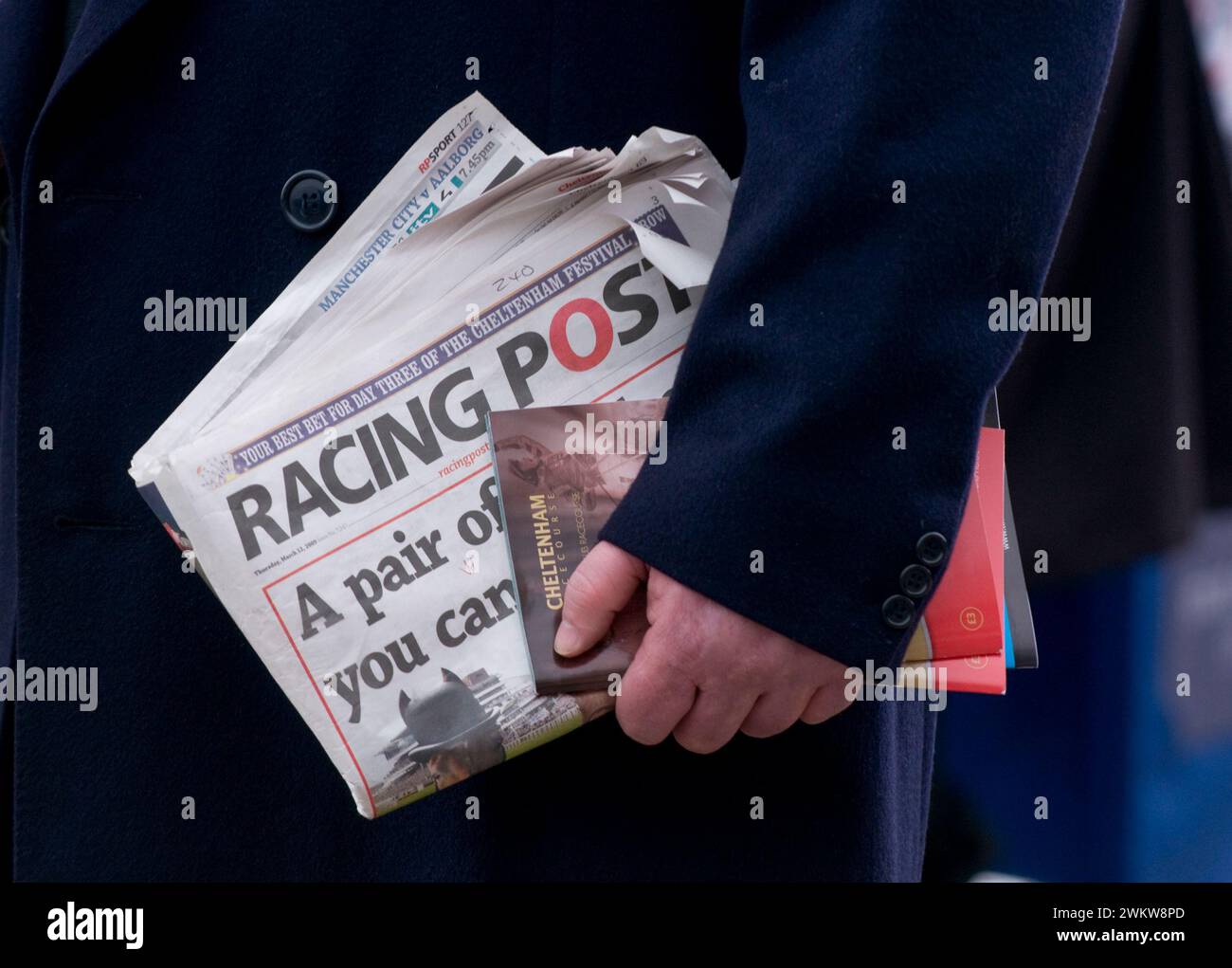 Man walking along with a copy of the Racing Post ready to bet on a ...