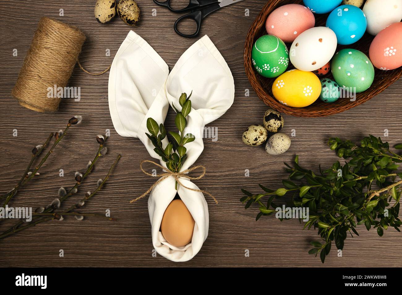 The process of making Easter decorations. Easter eggs and willow twigs on a wooden table. Stock Photo