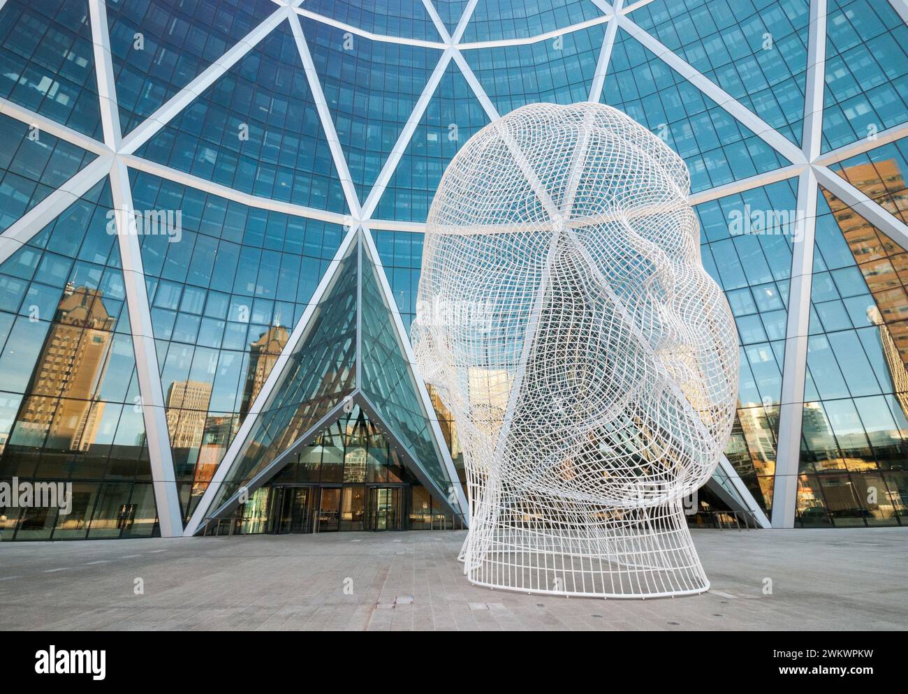 A twelve metre wire sculpture of a young girl's head by Spanish artist Jaume Plensa stands in front of Calgary's Bow Building. Stock Photo