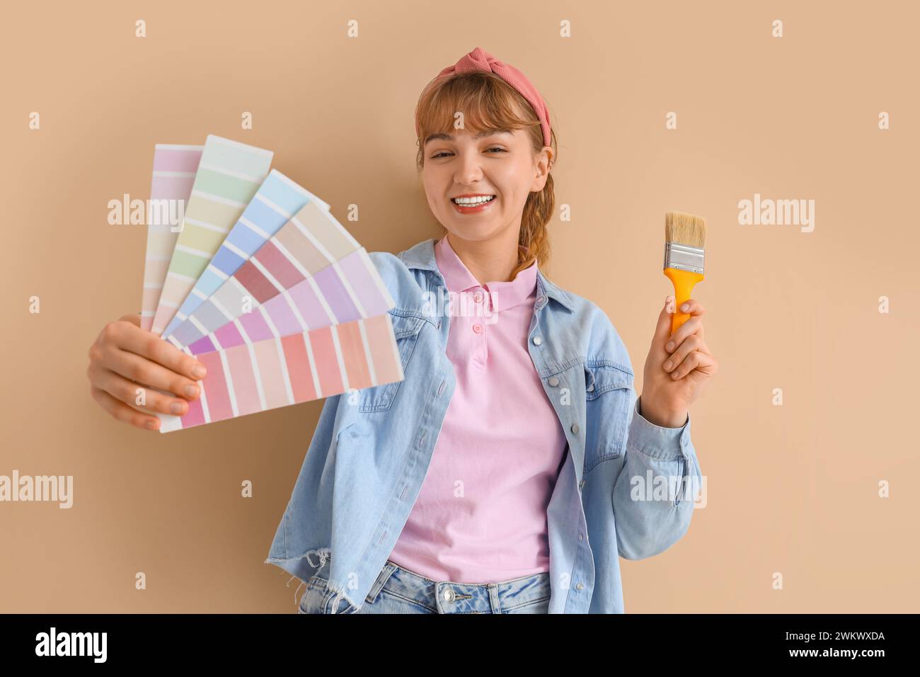 Young woman with paint color palettes and brush on beige background ...
