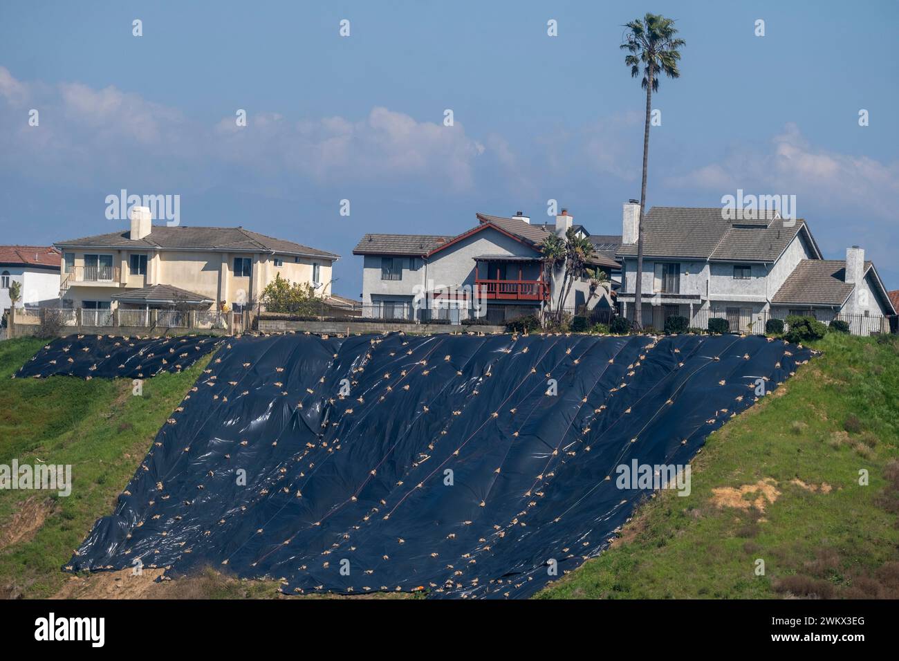 Residential homes near hill sides use tarps to safeguard against storm