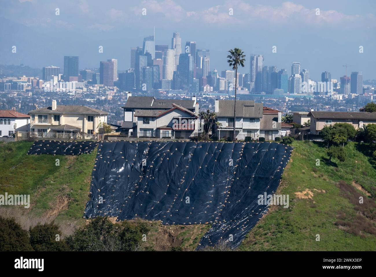 Residential homes near hill sides use tarps to safeguard against storm