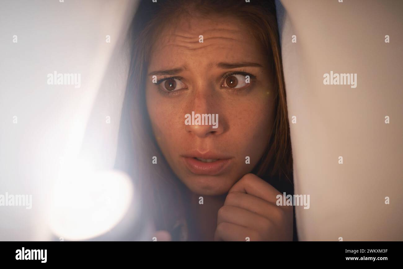 Flashlight, scared and woman with blanket on bed with anxiety, stress ...