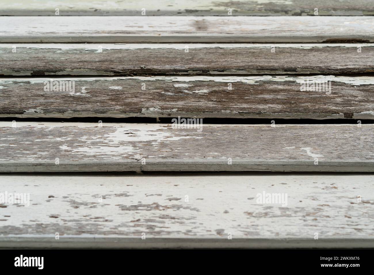 Close-up view of the old wooden building boards chipped and peeling painted white from old paint. Stock Photo