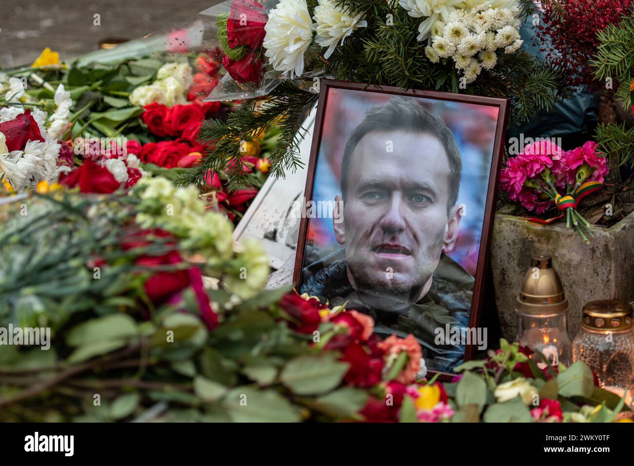 Flowers and candles laid at spontaneous memorial for Russian opposition leader Alexei Navalny, with portrait and messages wet from the snow and rain Stock Photo