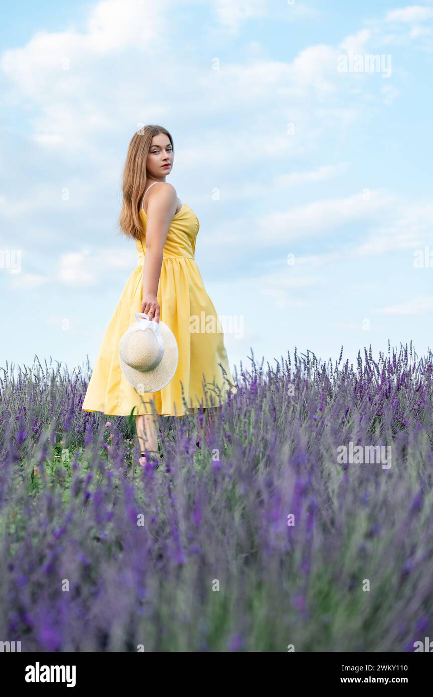 Ivano-Frankivsk, Ukraine August 5, 2023: A girl in a yellow dress walks in a lavender field, a young girl between lavender bushes. Stock Photo