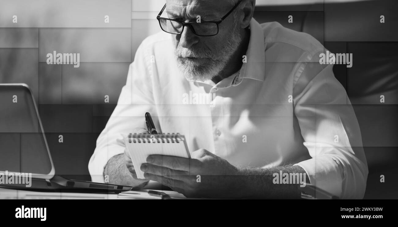 Senior businessman taking notes in office, hard light, geometric pattern Stock Photo