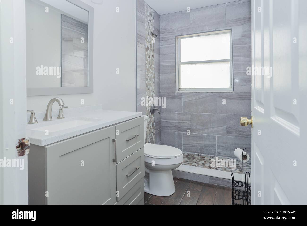 A white and gray bathroom with a sink, mirror, and cabinets Stock Photo