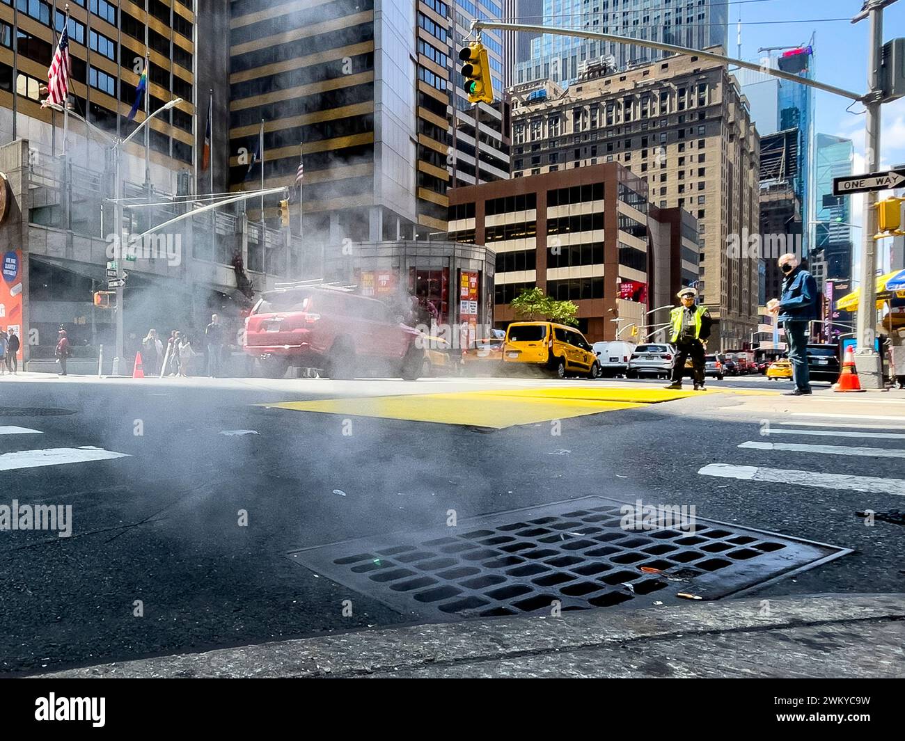 Photo of the vent in the middle of the Big Apple street, emanating smoke from the Manhattan subway in a city with heavy traffic. Stock Photo