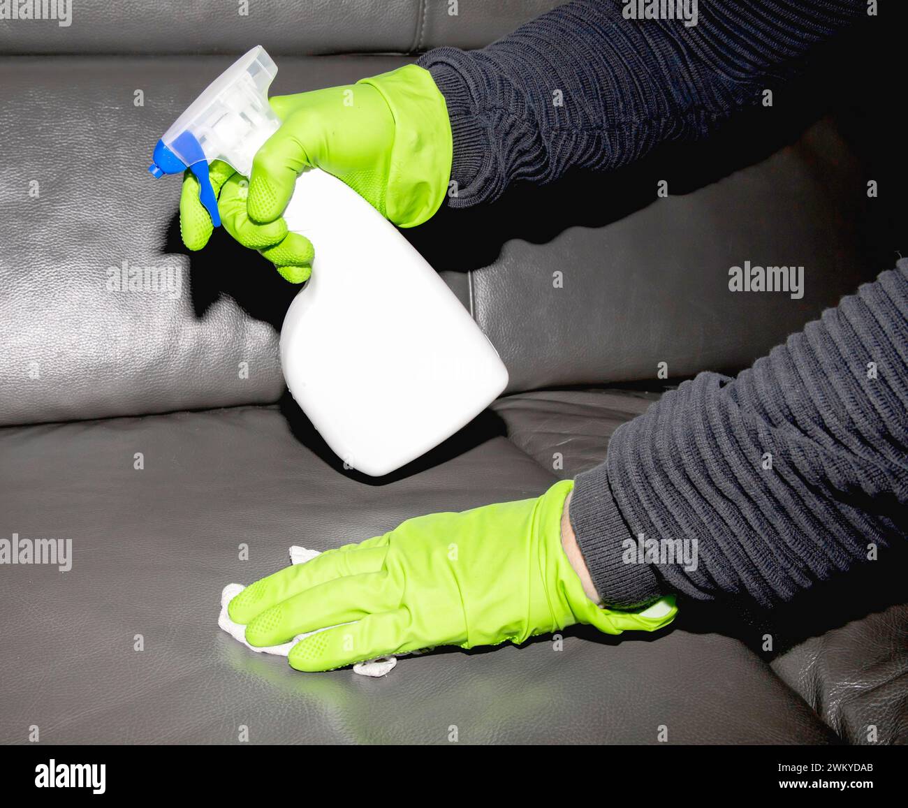 A person in rubber gloves cleaning the leather sofa and using cloth and