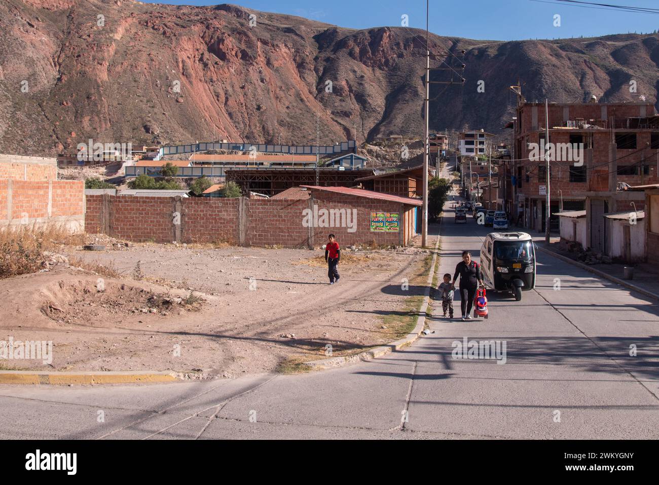 A father walking his child along a street in a town in the Sacred Valley near the Inca Trail in Peru Stock Photo