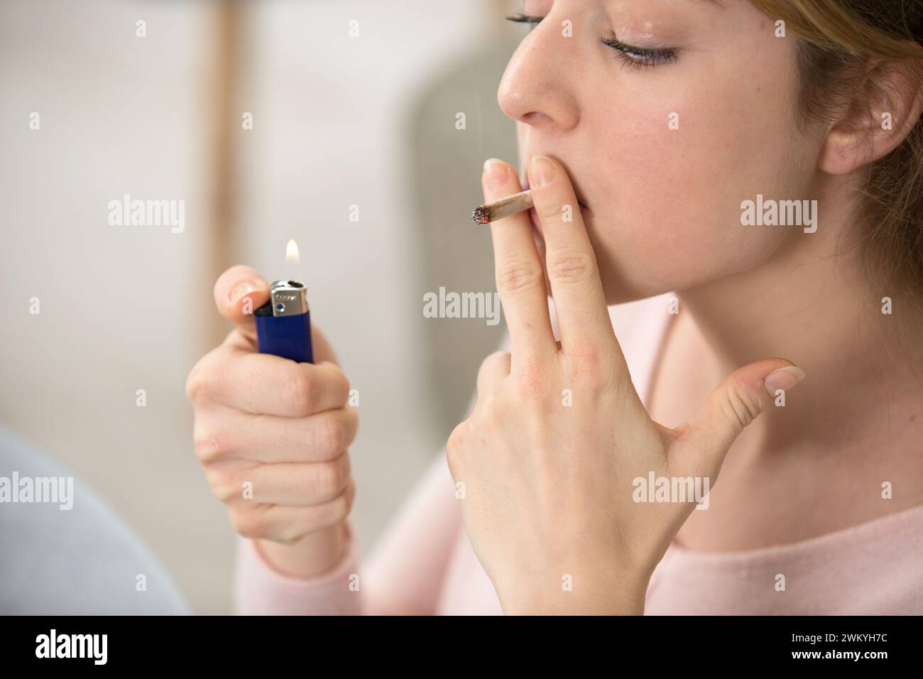 teenage girl lighting a hand rolled cigarette Stock Photo