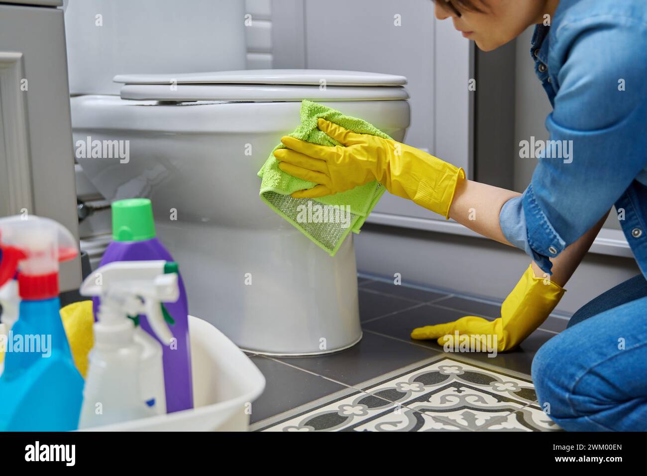 Woman in gloves using cleaning detergent clean toilet in bathroom Stock Photo - Alamy