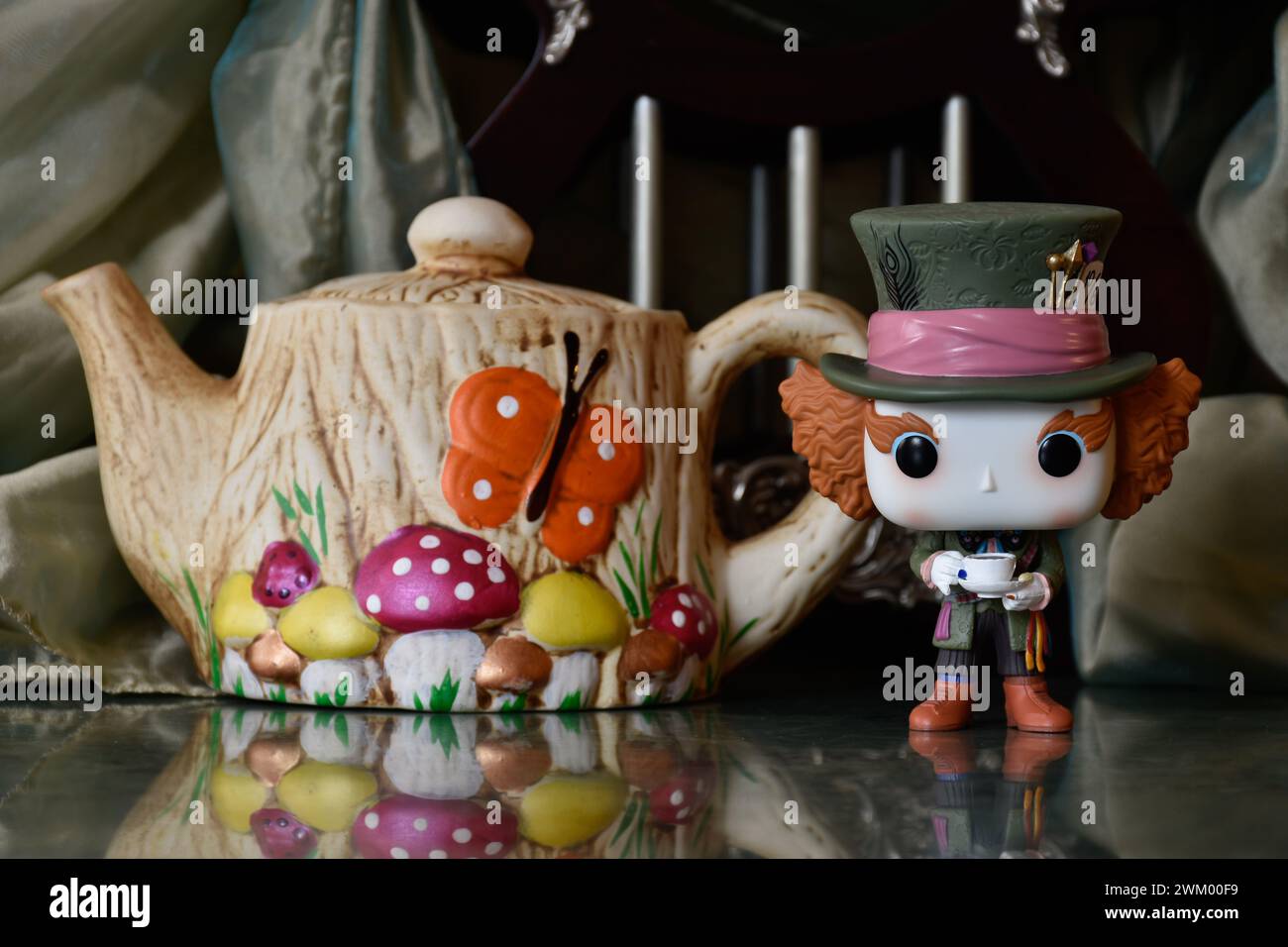 Funko Pop action figure of Mad Hatter from fantasy movie Alice in Wonderland. Handmade colorful teapot, fabulous palace, columns, reflection floor. Stock Photo