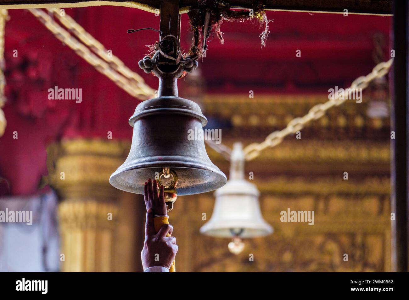 Devotee reaching to ring Temple bells at a Hindu temple in Varanasi , India Stock Photo