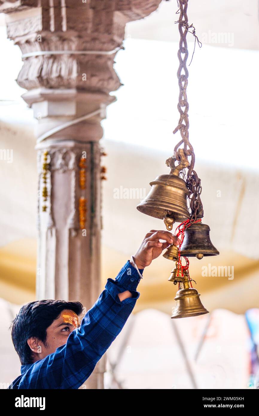 Devotee reaching to ring Temple bells at a Hindu temple in Varanasi , India Stock Photo