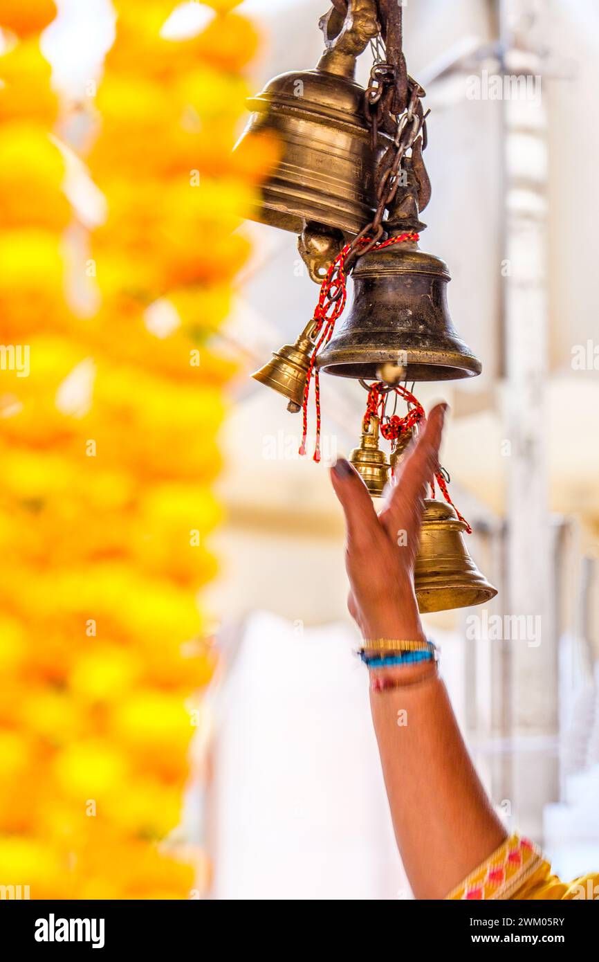 Devotee reaching to ring Temple bells at a Hindu temple in Varanasi , India Stock Photo