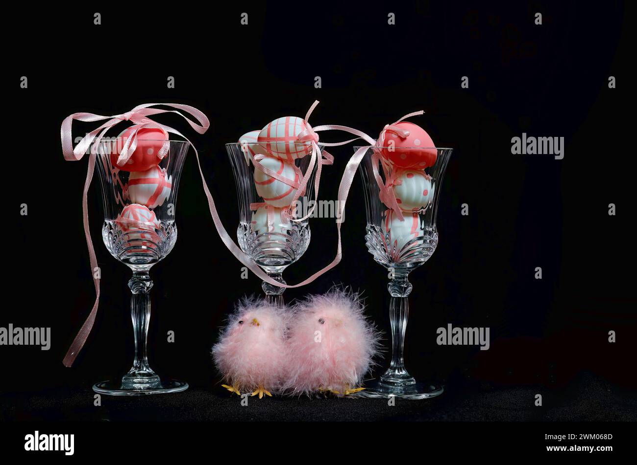 Pink and white easter eggs in glasses. Pink fluffy easter chicks on a table. Stock Photo