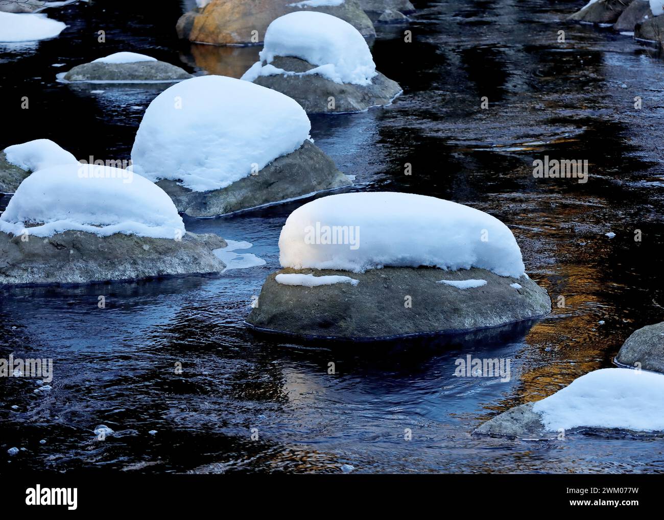 Snow covered stones in a river at daylight Stock Photo