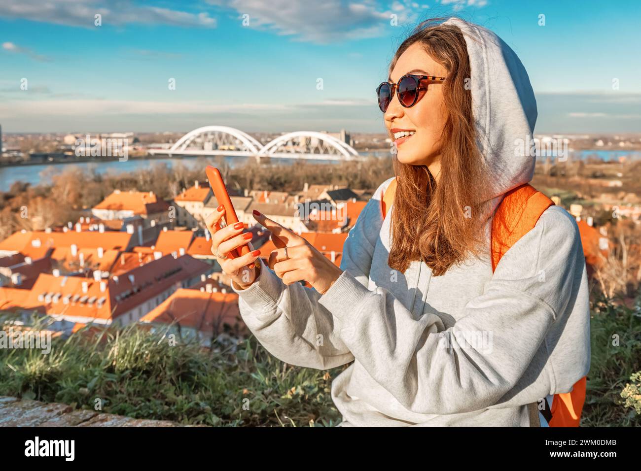 Amidst the charm of Novi Sad, a young traveler navigates the city streets, smartphone in hand, exploring its historic landmarks Stock Photo