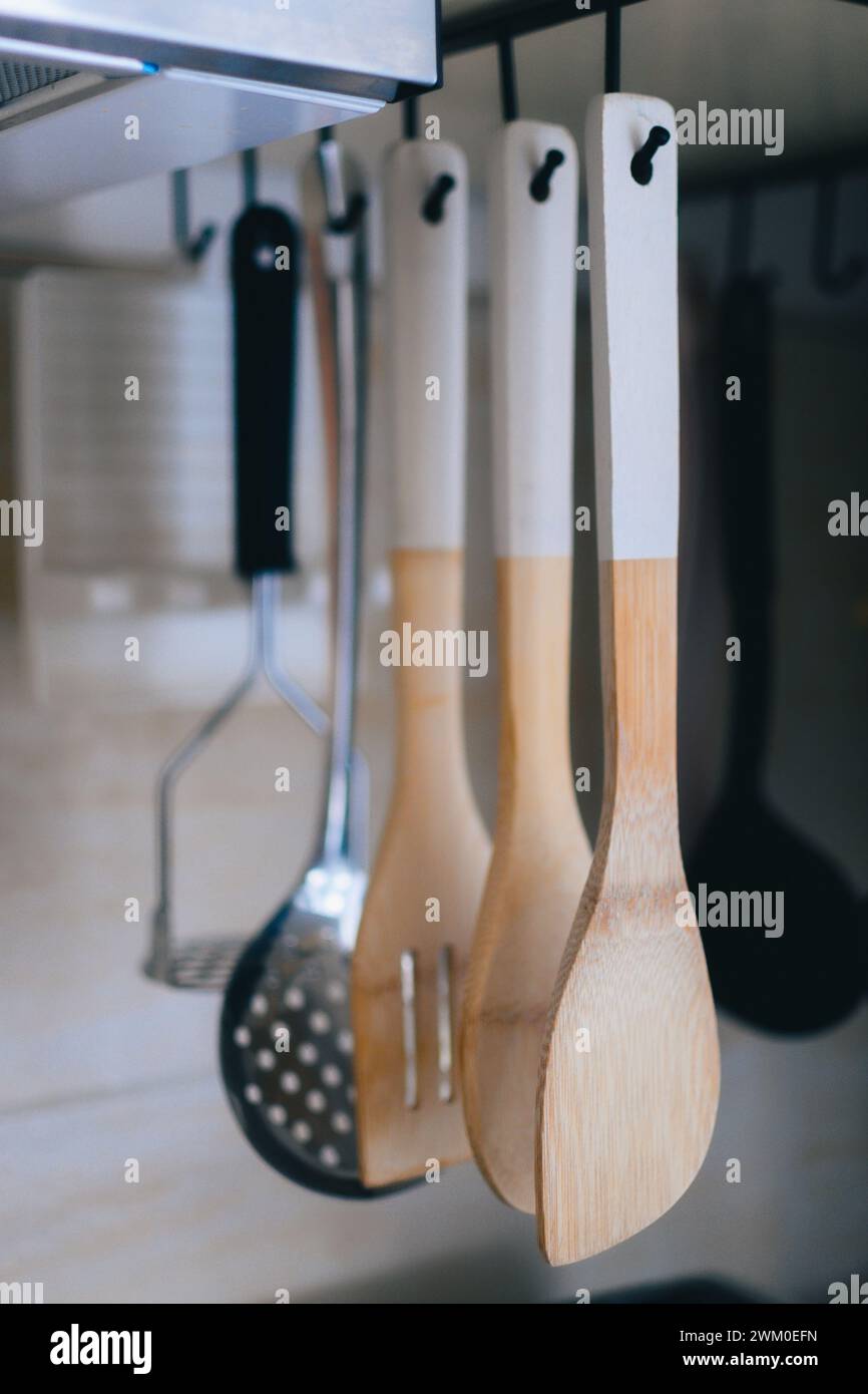 Wooden spoons hanging on hooks in a kitchen Stock Photo