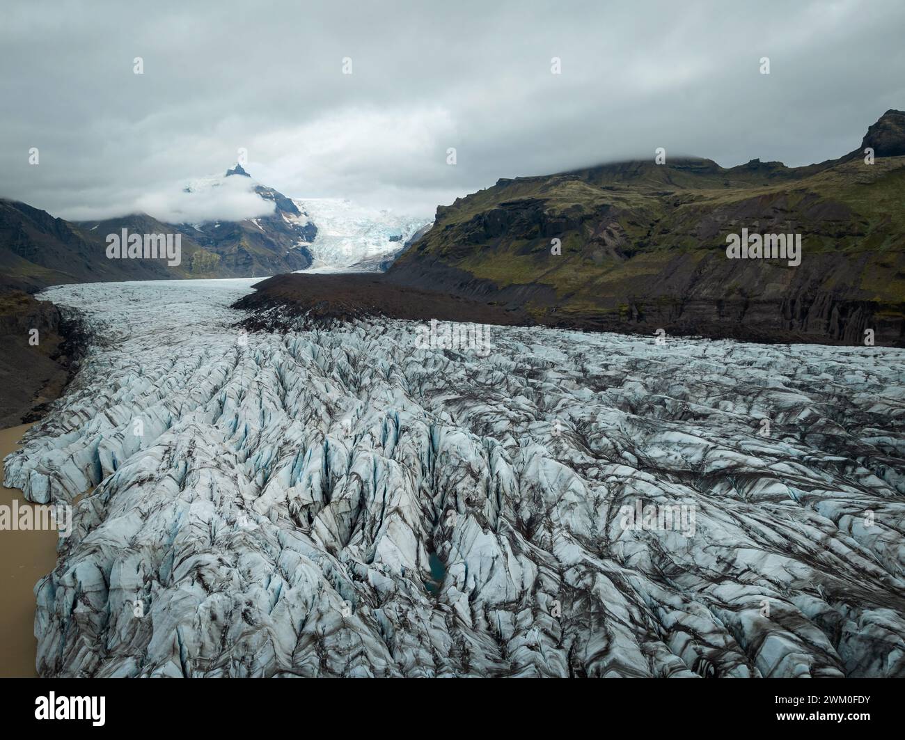 Surface of melting glacier tongue, black and white ice with volcanic ...