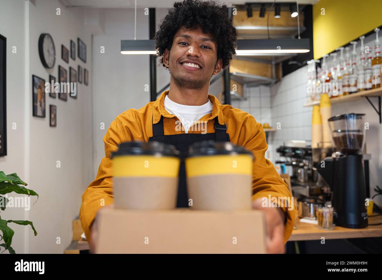 Smiling barista holding takeaway coffee cups at cafe Stock Photo