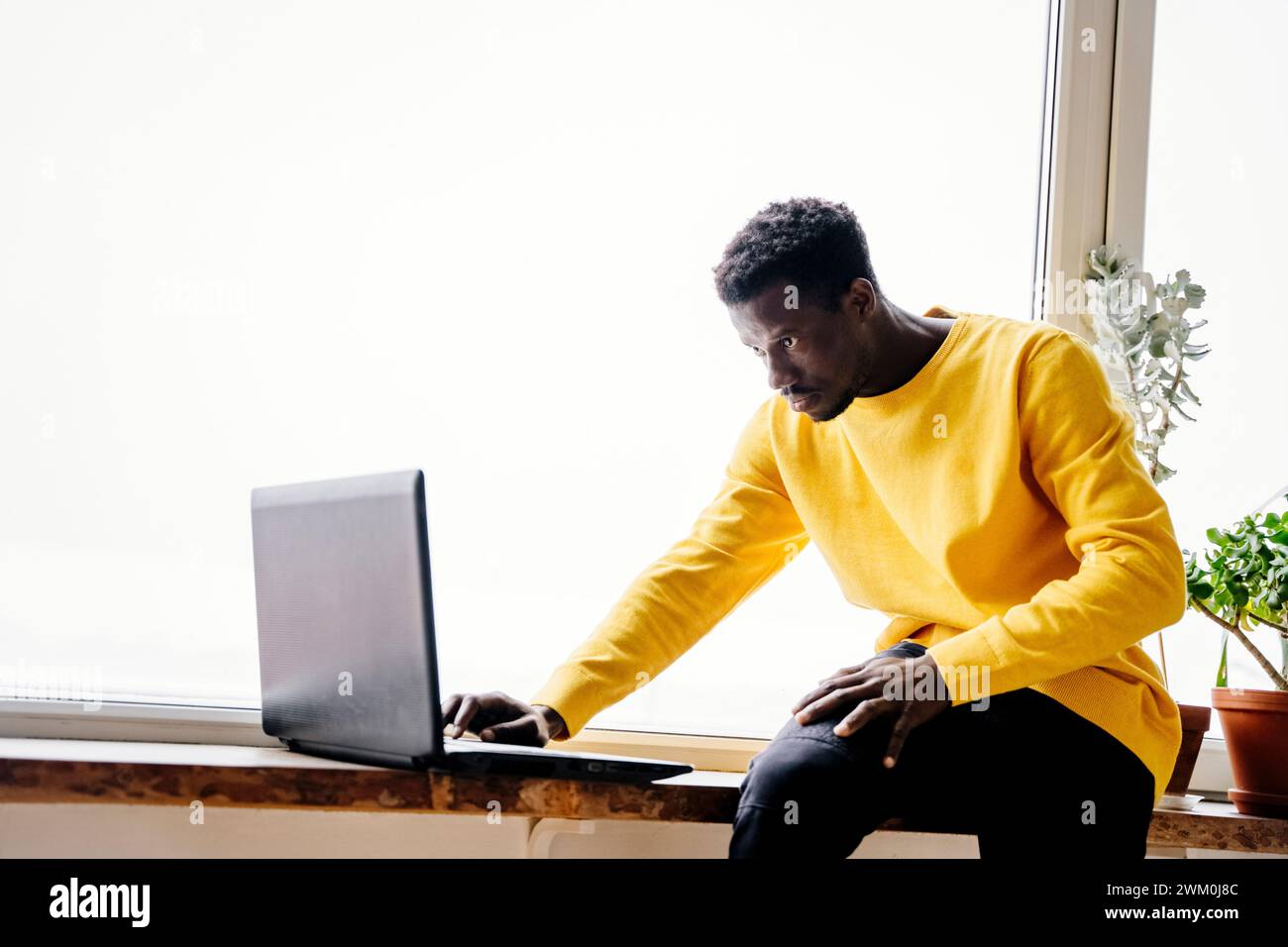 Man using laptop near window at home Stock Photo