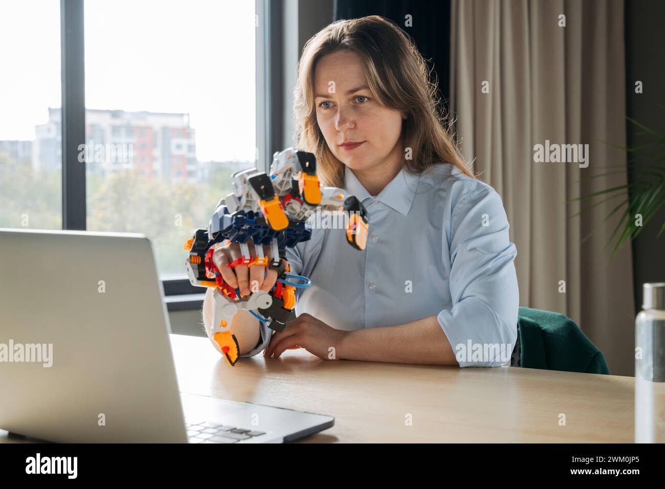 Engineer working on robot arm project and using laptop in office Stock Photo