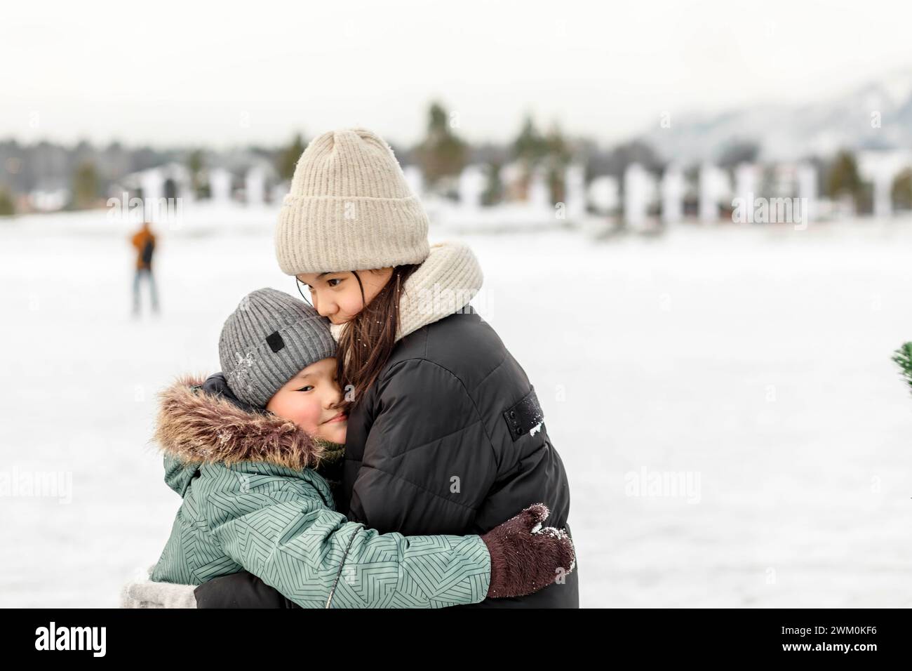 Brother hugging sister and wearing warm clothing in winter Stock Photo