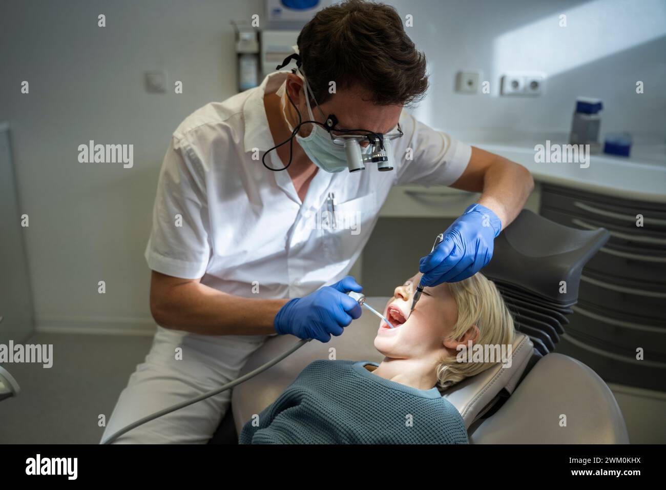 Dentist examining patient with medical equipment in clinic Stock Photo
