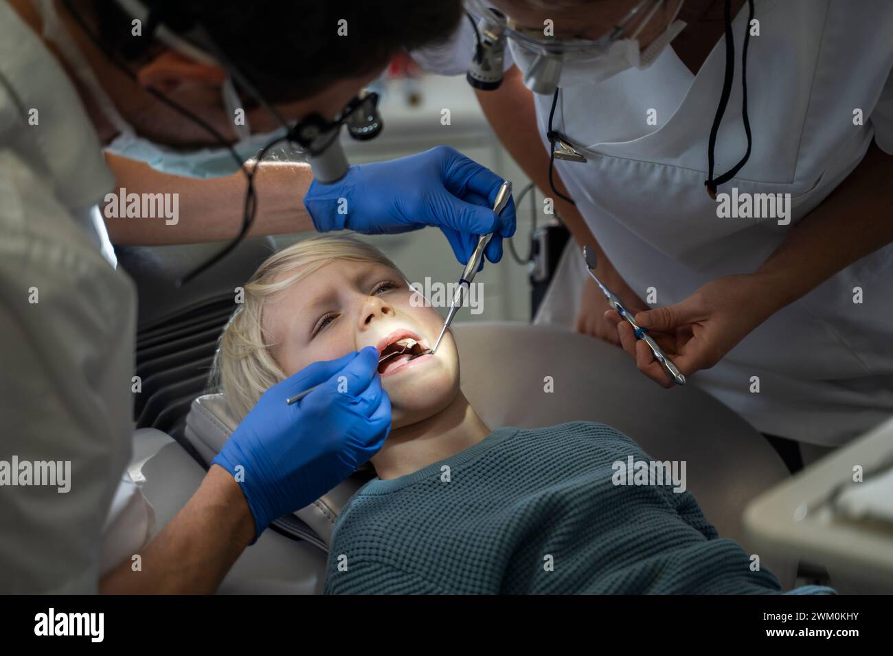 Dentist examining patient's teeth near assistant in clinic Stock Photo