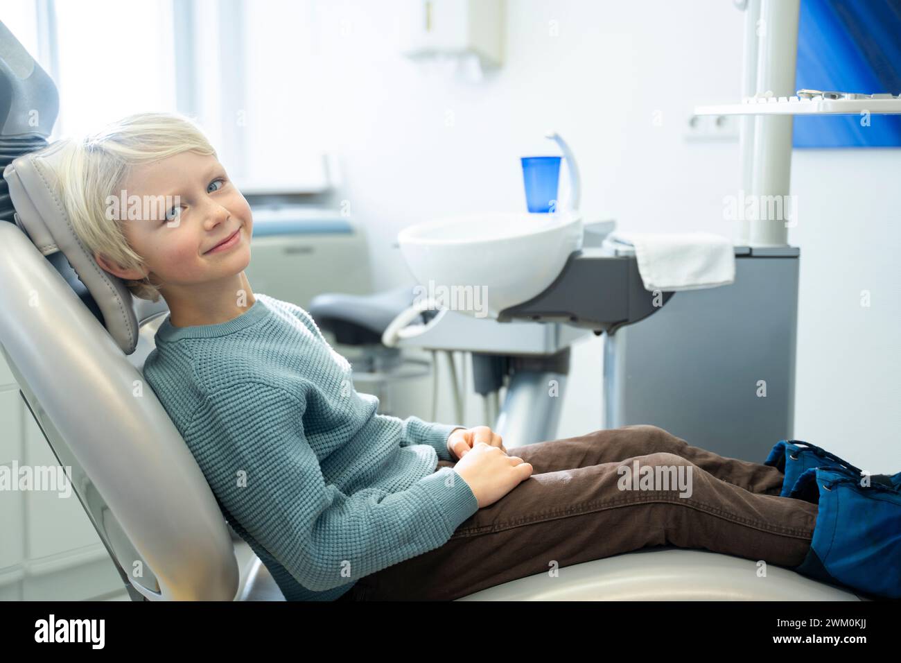Smiling boy sitting on chair for dental checkup in clinic Stock Photo
