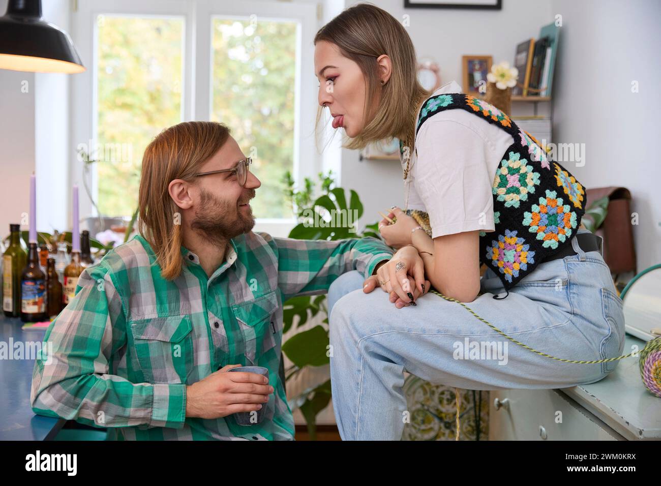 Woman teasing happy man sitting at home Stock Photo