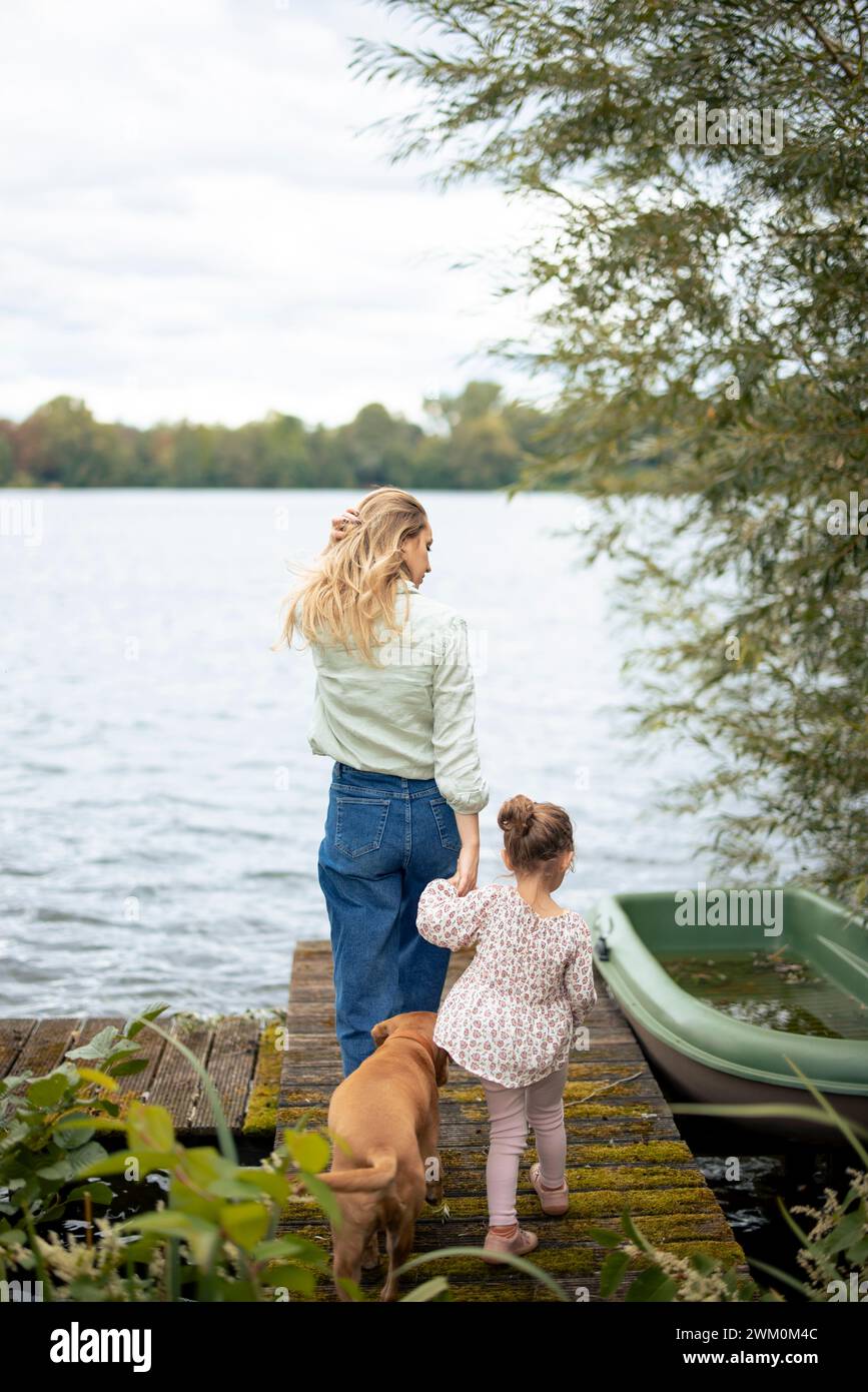 Mother and daughter walking with dog on jetty Stock Photo