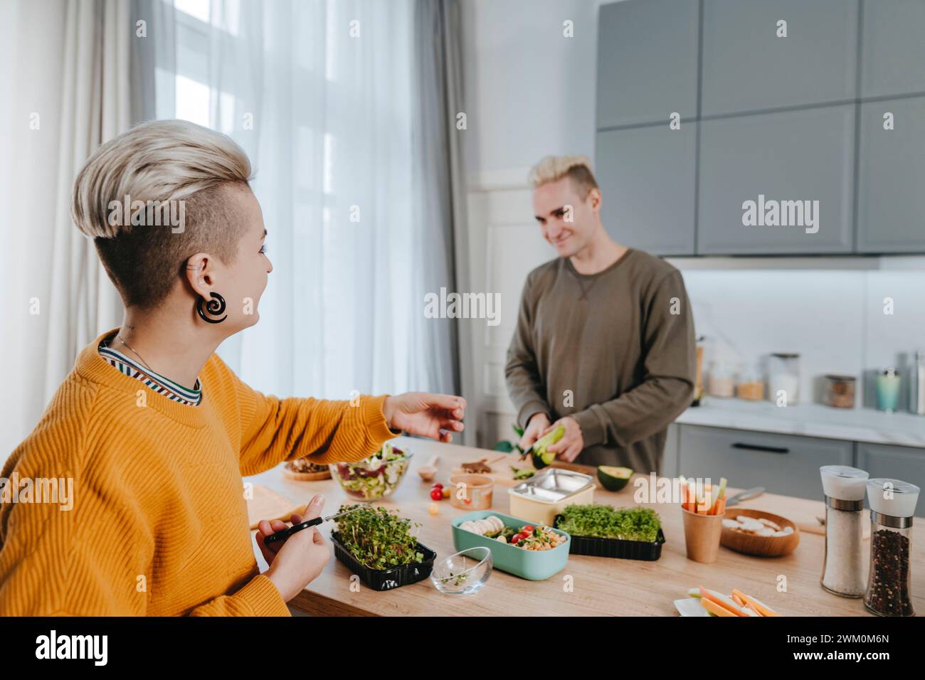Happy woman cutting microgreen with man preparing lunch boxes Stock Photo