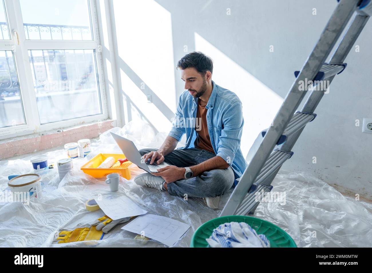 Young man using laptop in room under renovation Stock Photo