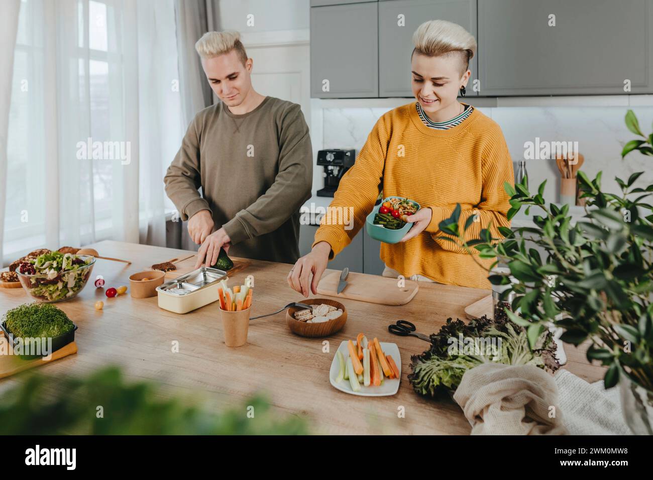 Happy couple preparing healthy food for lunch boxes in kitchen at home Stock Photo