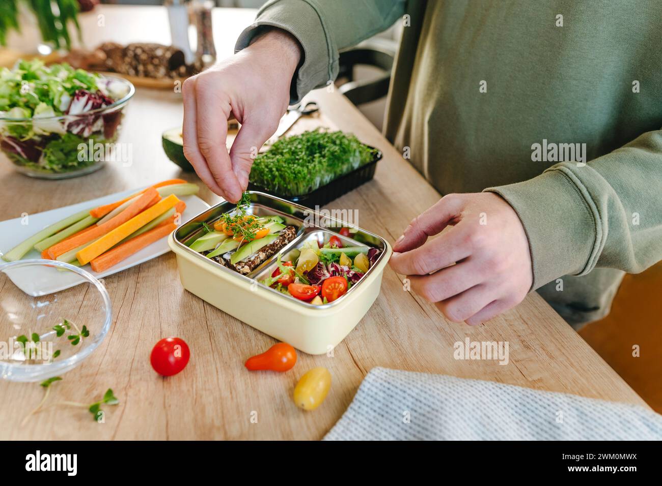 Man garnishing microgreen over vegetarian food in lunch box Stock Photo