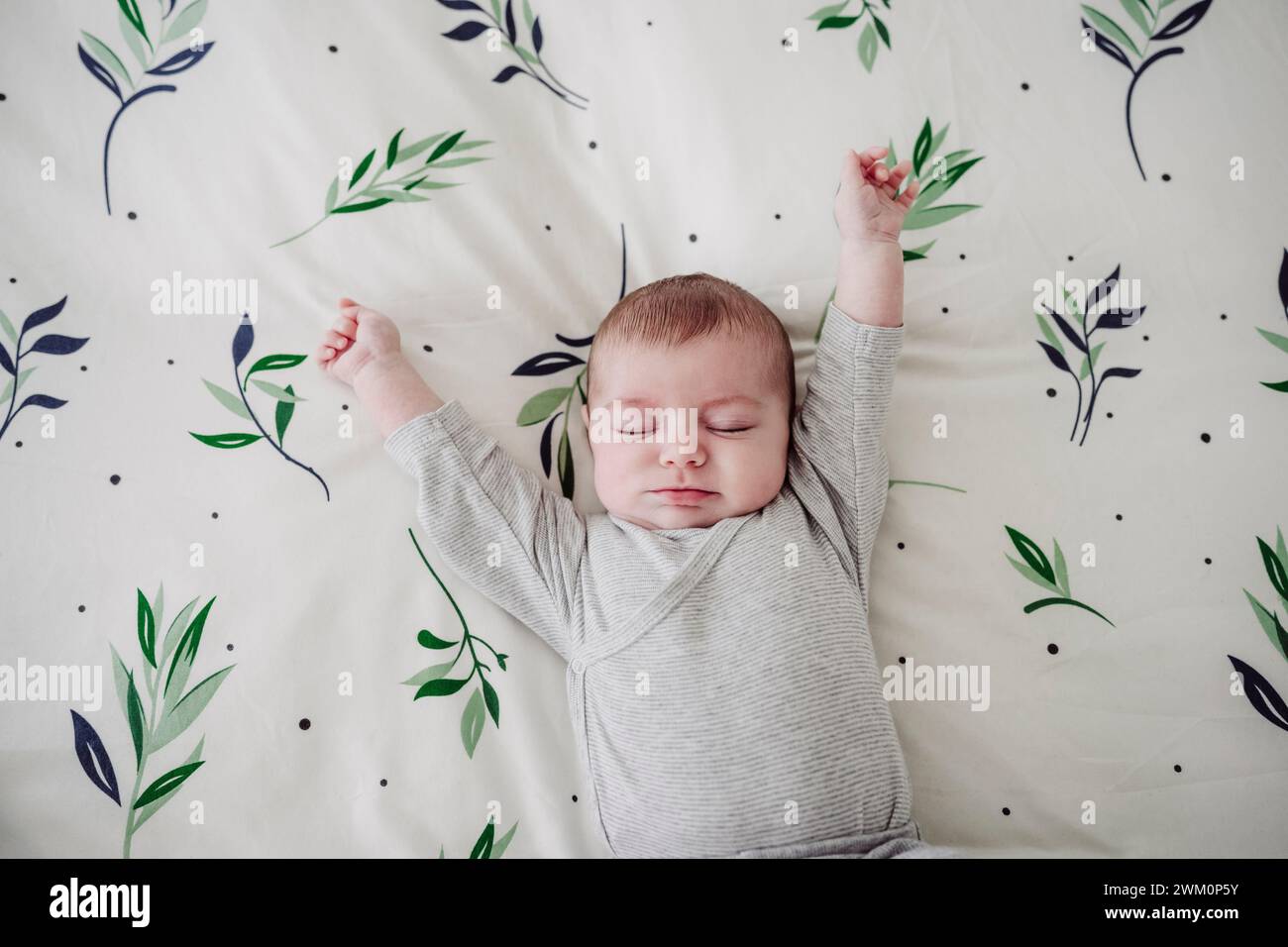 Cute baby girl stretching arms lying in bed at home Stock Photo