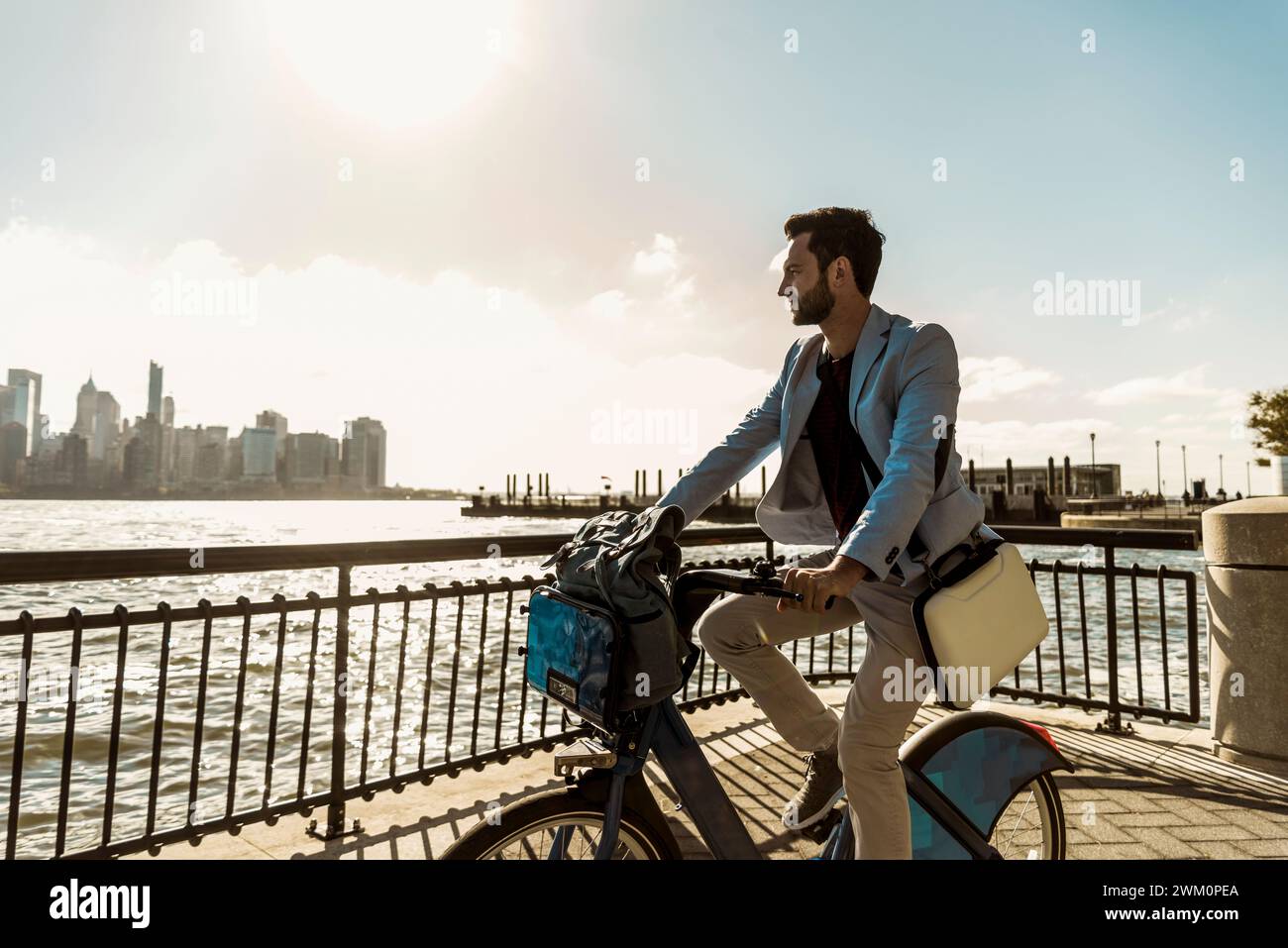 Businessman cycling on promenade in city Stock Photo