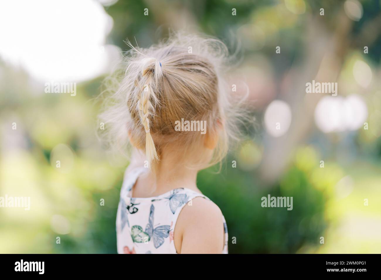 Little girl with flowing hair stands near a tree and points to it. Back ...