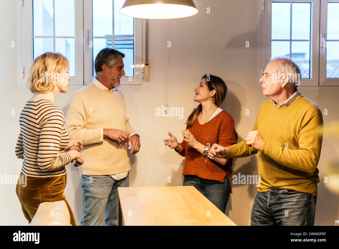 Smiling couples standing together and talking with each other at home Stock Photo