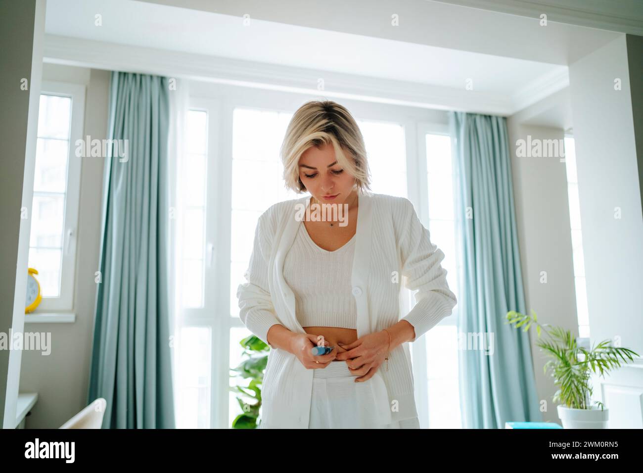 Woman with diabetes injecting insulin in stomach at home Stock Photo